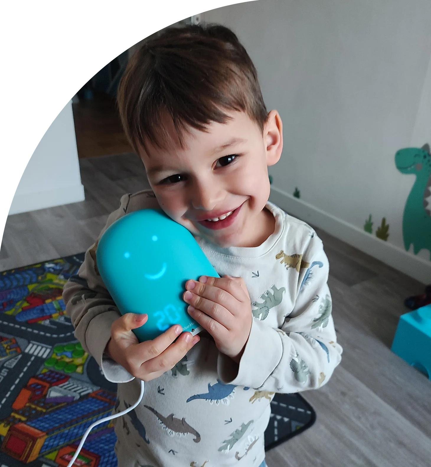 Ein Junge hält ein blaues Ballon-Luftballonlächeln und schaut freudig in die Kamera.